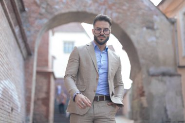 Eski bir ortaçağ kasabasında el ele poz veren ve gözlük takan yakışıklı iş adamının portresi.