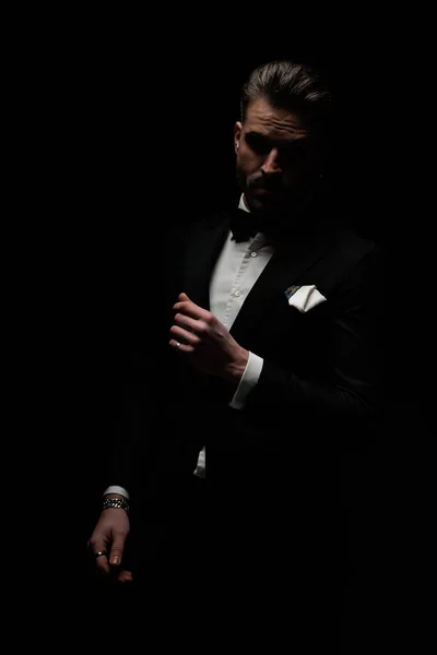 Tajemný Elegantní Muž Černém Smokingu Sebevědomě Pózuje Před Černým Pozadím — Stock fotografie