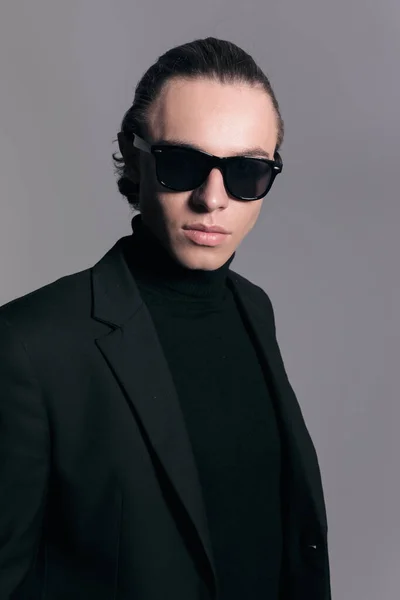 Fashion picture of sexy businessman wearing cool sunglasses and wearing a nice outfit against gray studio background