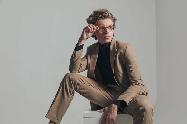 Smart Casual Mężczyzna Siedzi Trzyma Łokieć Kolanie Podczas Mocowania Okularów — Zdjęcie stockowe