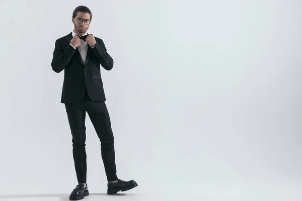Elegant Businessman Glasses Adjusting Black Bowtie Posing Front Grey Background — Stock Photo, Image