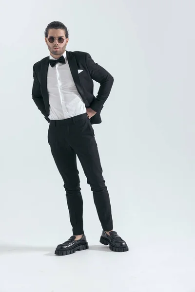 セクシーなエレガントな男ですサングラス調整スーツパンツとポーズの前にグレーの背景 — ストック写真