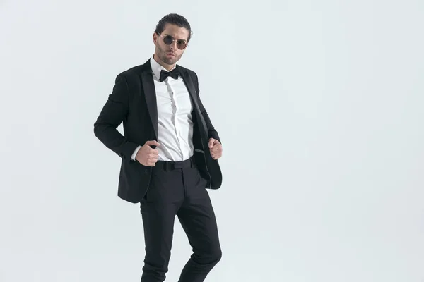Elegáns Fiatal Férfi Szemüveggel Állító Fekete Szmoking Kabát Előtt Szürke — Stock Fotó