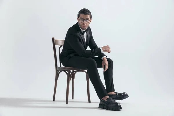 Vista Lateral Del Impactado Hombre Elegante Esmoquin Negro Sentado Con — Foto de Stock