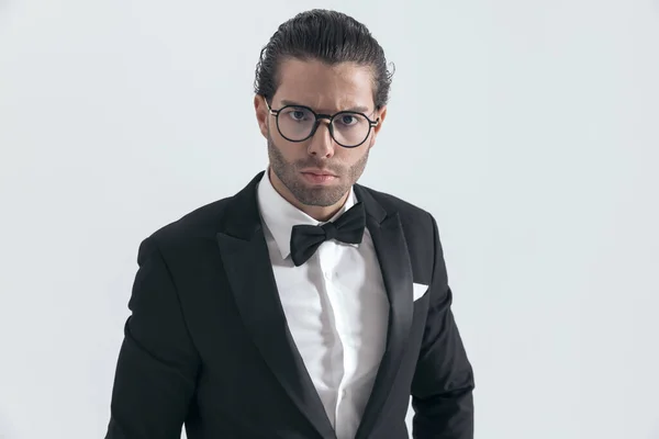 Jovem Homem Elegante Com Óculos Smoking Preto Franzindo Testa Posando — Fotografia de Stock