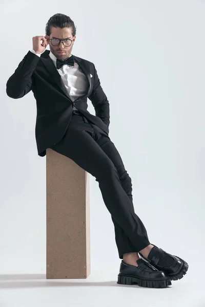 Elegante Joven Novio Esmoquin Negro Gafas Fijación Sentado Con Mano — Foto de Stock