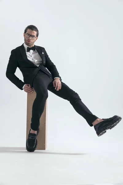 Σέξι Άντρας Μαύρο Σμόκιν Γυαλιά Που Κάθεται Πόδι Στον Αέρα — Φωτογραφία Αρχείου