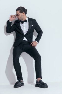 Genç işadamı güneş gözlüğünü takıyor ve beyaz stüdyo arka planında gözlük takıyor.