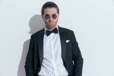 Yakışıklı iş adamı kameraya derin bir bakışla bakıyor, beyaz stüdyo arka planına karşı gözlük takıyor.