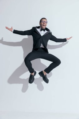 Genç işadamı heyecan dolu bir havada, beyaz stüdyo arka planına karşı gözlük takıyor.