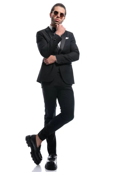 Bonito Empresário Tocando Queixo Cruzando Pernas Vestindo Óculos Contra Branco — Fotografia de Stock