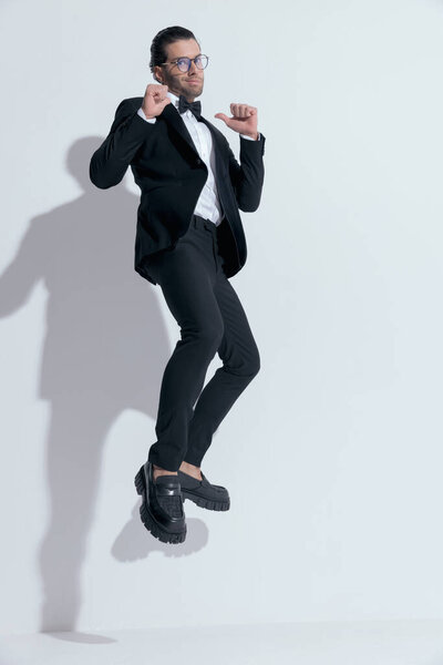 handsome businessman jumping an pointing to himself with pride, wearing glasses against white studio background
