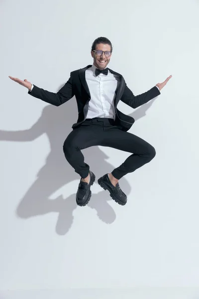 Elegancki Biznesmen Squatting Powietrzu Śmiech Noszenie Okularów Białym Tle Studio — Zdjęcie stockowe