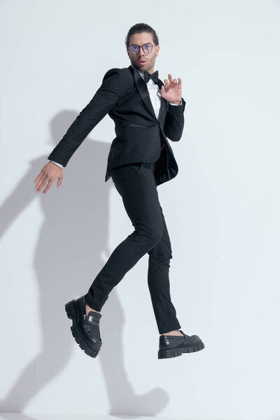 sexy businessman jumping with style in the air, wearing glasses against white studio background