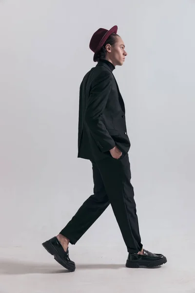 厳しい態度で歩く若いビジネスマンのファッション写真とグレーのスタジオの背景に対してスタイリッシュな衣装を身に着けている — ストック写真