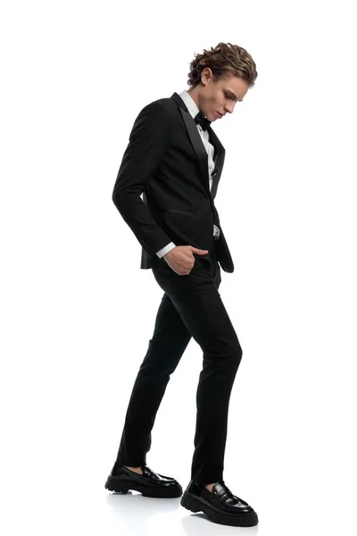 エレガントなビジネスマンが頭を下げて白いスタジオの背景に正式な衣装を着て歩き — ストック写真