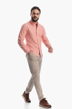 Ekose gömlekli, kendine güvenen sakallı bir adamın, stüdyoda beyaz arka planda el ele yürürken tüm vücudu.