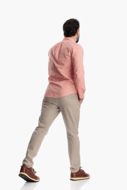 Ekose gömlekli genç bir adamın fotoğrafının arkasında el ele tutuşup stüdyoda beyaz arka planda yürürken.