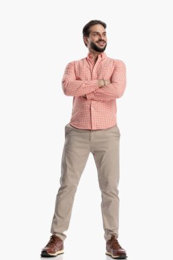 Ekose gömlekli gururlu genç adam kollarını kavuşturup beyaz arka planda gülümsüyor.