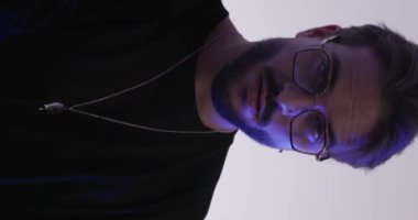 Polis ışıkları açık gri arka planda yanıp sönerken gözlüklü tehlikeli bir adam yan tarafa bakıyor.