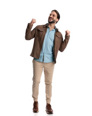 Gözlüklü yakışıklı genç adam yumruklarını kaldırdı, yukarı baktı ve beyaz arka planda durup zafere tezahürat yaptı.