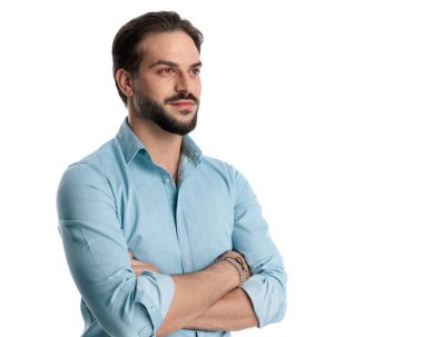 Stüdyoda beyaz arka planda sakallı ve kollarını kavuşturan yakışıklı, sıradan bir adam.