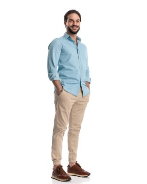 # Gururlu, sakallı, el ele tutuşmuş, beyaz arka planda gülümseyen genç bir adam.