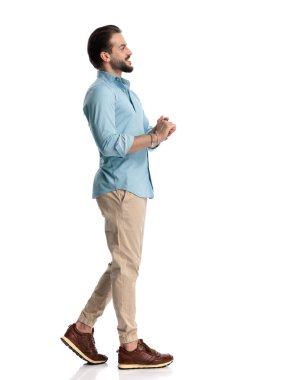 Kendine güveni olan genç bir adamın el ele tutuşup beyaz arka planın önünde yürümesinin yan görüntüsü.