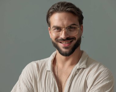 Gözlüklü ve gri arka planda gülümseyen mutlu sıradan bir adamın portresi.