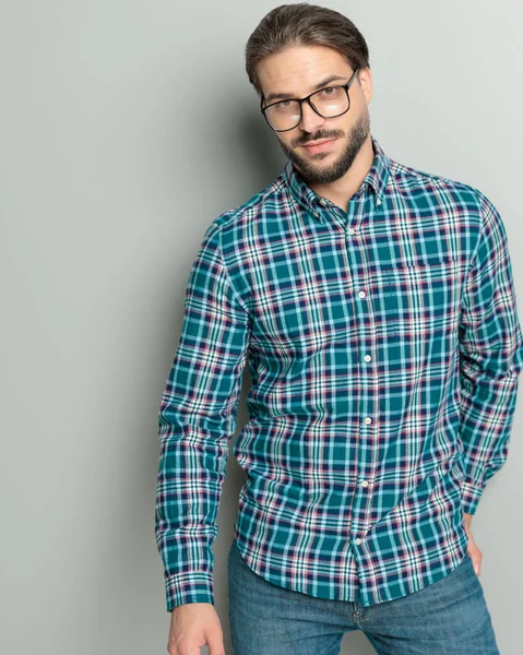 ハッピーカジュアルな男性は 平らなシャツを着て バックポケットで手を握り 灰色の背景の前に微笑んでいる — ストック写真