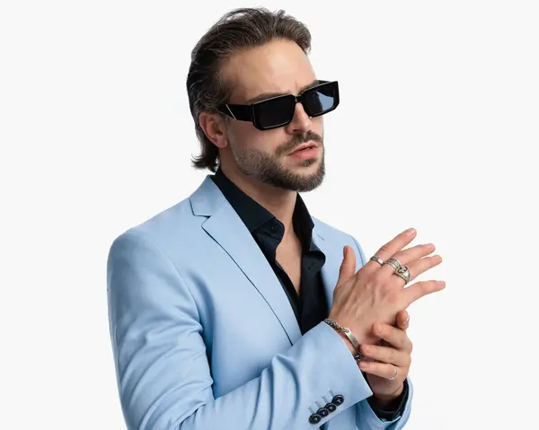 stock image attractive young man with sunglasses touching palms and looking away while posing in front of white background