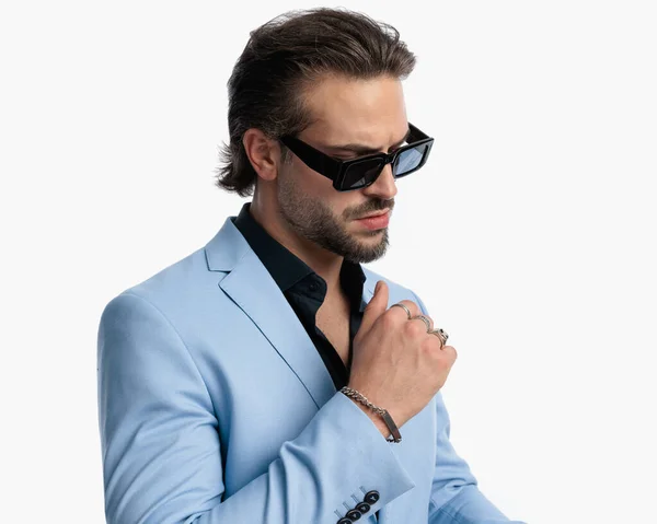 白い背景の前に見下ろし ポーズするサングラスを持つクールなファッション男性の側面ビュー — ストック写真