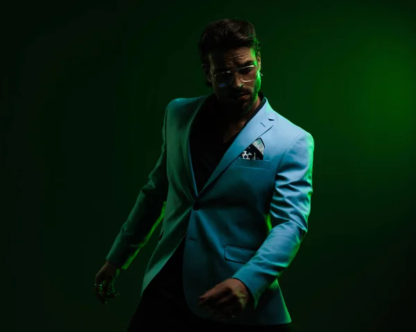 緑のライトが付いている黒い背景の前に腕を握るメガネが付いている確信したビジネスマン — ストック写真