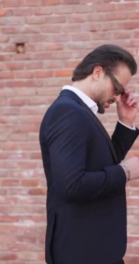 Takım elbiseli kendine güvenen sakallı adam Romanya 'nın eski bir şehrinde yürürken gözlük takıyor ve el ele tutuşuyor.
