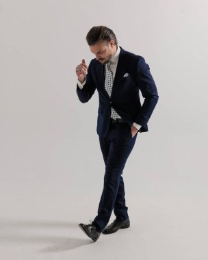 Kendine güvenen bir işadamı gri arka planda el ele yürür. 