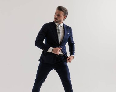 Gri arkaplanda lacivert takım elbise arayan şık bir adam. 