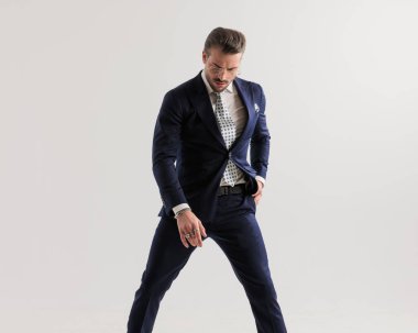 Gözlüklü havalı bir üst sınıf adam el ele tutuşup gri arka planda havalı poz veriyor.