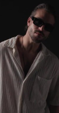 Güneş gözlüklü seksi genç adam kırmızı ve mavi ışıkların önünde şehvetli bir görünüm sergiliyor.