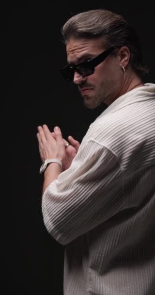 어두운 배경의 움직이고 선글라스를 배열하는 손바닥을 만지는 매력적인 남자의 뒤보기 — 비디오