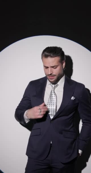 サイドビューでグレーの背景にスーツを配置し移動しながら 傲慢で ポケットに手を握っている高級ビジネスマンの垂直ビデオ — ストック動画