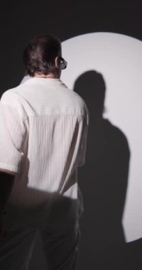 Beyaz gömlekli, güneş gözlüklü, kollarını hareket ettiren ve gri arka planda kollarını kavuştururken gülümseyen sıradan bir adamın arka plan videosu.