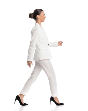 Beyaz arka planda gülümseyen ve yürüyen, topuz saçlı zarif genç iş adamının yan görüntüsü. 