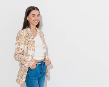 Gri arka planda kot pantolonun cebinde el ele tutuşurken gülümseyen güzel mutlu kız.