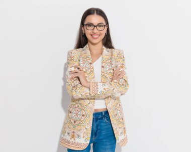 Gözlüklü heyecanlı iş kadını kollarını kavuşturup gri arka planda gülümserken mutlu oluyor.