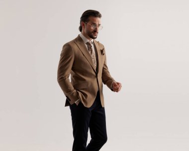 Gözlüklü seksi sakallı adam el ele tutuşup gri arka planda yan yana yürüyordu.