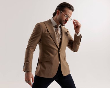 Zarif iş adamının gri arkaplanının önündeki gözlüklere bakması ve onları ayarlaması.