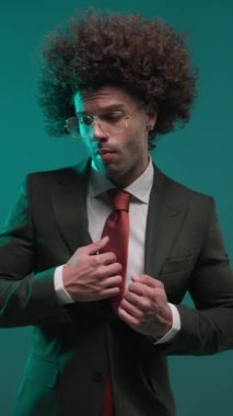 Şehvetli bir erkeğin kıyafetlerini ayarlarken, dudaklarına ve yüzüne dokunurken ve renkli bir arkaplan arkaplanının arkasına bakarken yan görünüm.