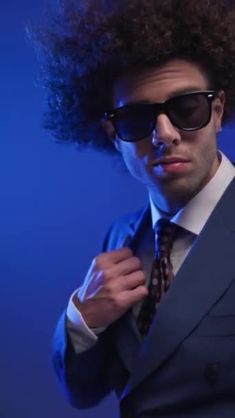클로즈업 비디오의 섹시한 곱슬머리 남자와 선글라스 소송을 뒤에서 화려한 배경의 — 비디오