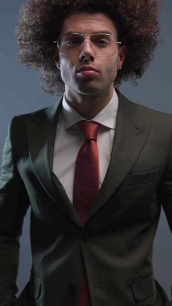 ポケットに手を握り 灰色の背景の前に黒いスーツを開けるクールなファッションビジネスマンの垂直ビデオ — ストック動画