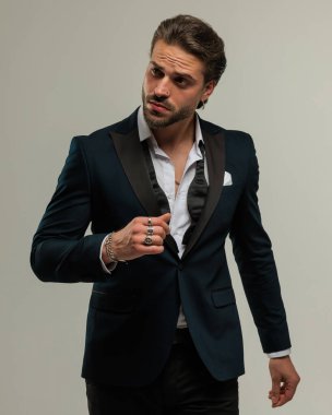 Smokinli, papyonlu genç ve seksi bir iş adamı. Gri arka planda yürümeye çalışıyor.